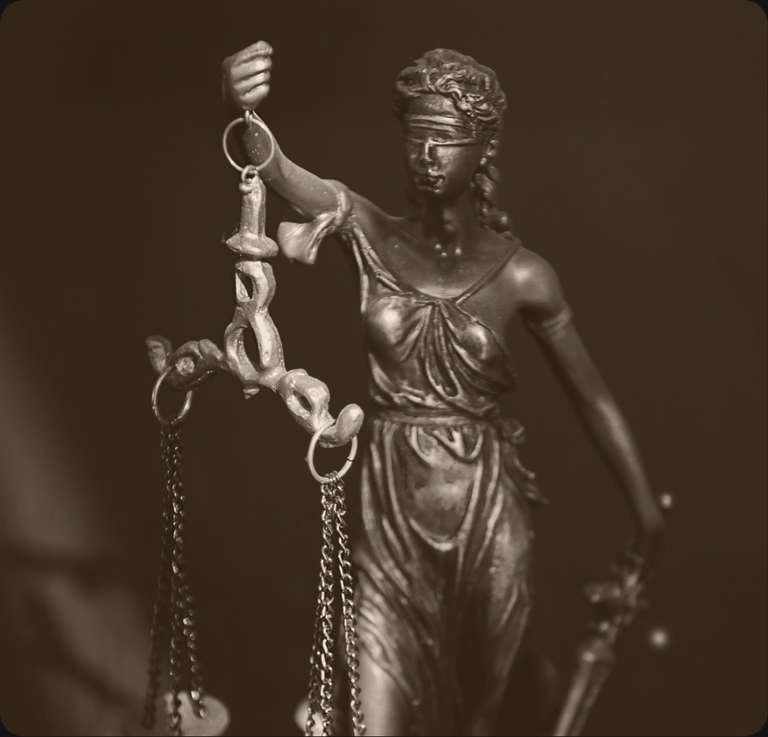 Mosiężna figura Temidy z wagą i opaską na oczach, zdjęcie w ciepłej tonacji