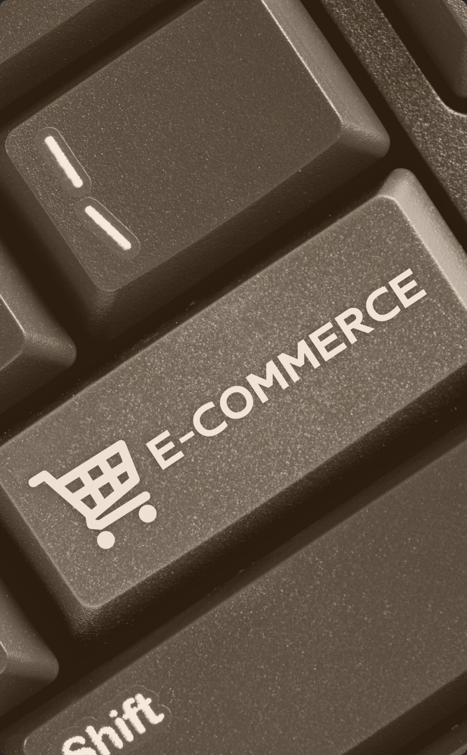 Zbliżenie czarnej klawiatury komputera z jednym niebieskim klawiszem z napisem E-COMMERCE i ikoną koszyka na zakupy