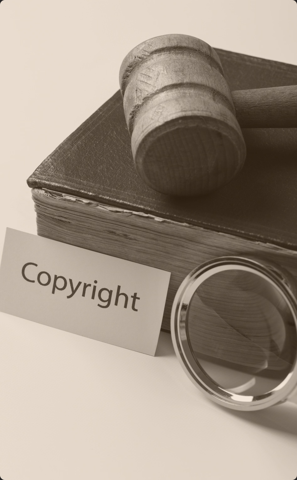 Młotek sędziowski na oprawionej księdze, obok karta z napisem Copyright i lupa